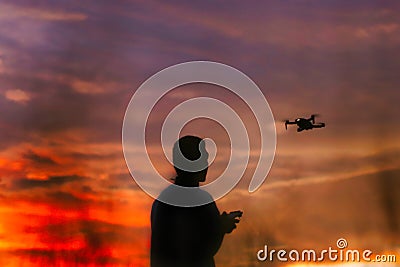 Silhouette of a boys piloting a drone on A Rural Setting on sunset Stock Photo