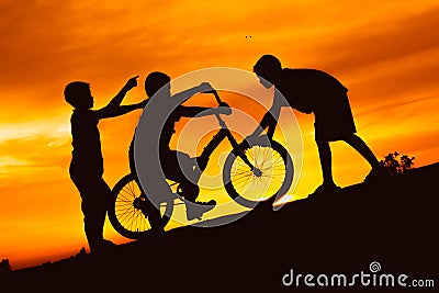 Silhouette boys riding bicycle at sunset or sunrise Stock Photo