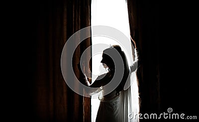 Silhouette of a bride standing before a bright window Stock Photo