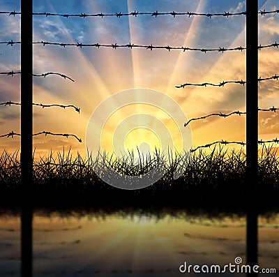 Silhouette of a broken border fence with barbed wire Stock Photo