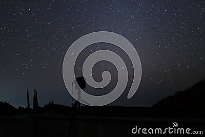 Silhouette camera on tripod with beautiful stars on night sky background. Stock Photo