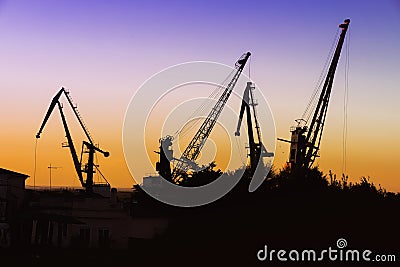 Silhouette of of cargo cranes. Port wharf landscape. Bright sunset, bright sky. Evening in the port Stock Photo