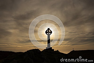 Silhouette of a Celtic cross with the evening sun directly behind it. With a cross in the background Stock Photo