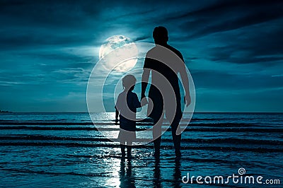 Silhouette of child holding hands her father, standing in the se Stock Photo