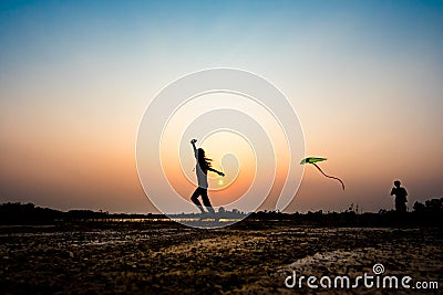 Silhouette of children flying a kite at sunset Stock Photo