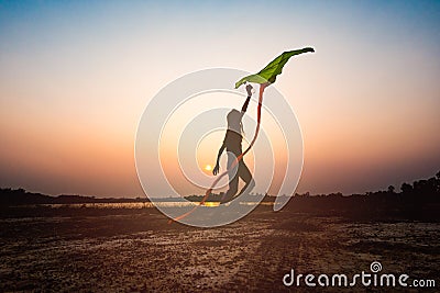 Silhouette of children flying a kite at sunset Stock Photo