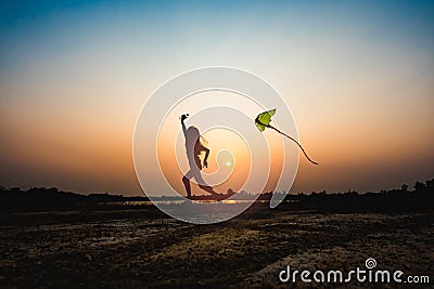 Silhouette of children flying a kite at sunset Stock Photo