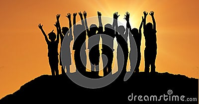 Silhouette children with hands raised on hill against orange sky Stock Photo
