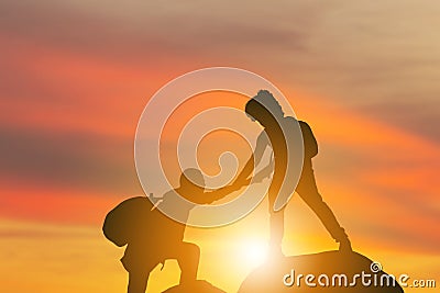 Silhouette of climbers man gived hand for pull hikers team to peak of mountain for work together, Sport and Teamwork Concept Stock Photo
