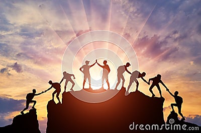 Silhouette of climbers who climbed to the top of the mountain thanks to mutual assistance and teamwork Stock Photo