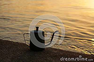 silhouette of a coffee kettle at the lake Stock Photo