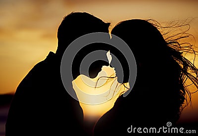 Silhouette couple enjoying romantic moment with their foreheads touching against sunset background. Unknown boyfriend Stock Photo
