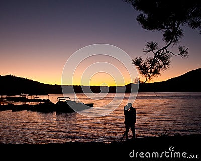 Silhouette of couple kissing on the lake at sunset Stock Photo