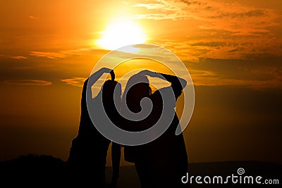 Silhouette of couple in love watching a sunset on the mountains, moment of reflection Stock Photo