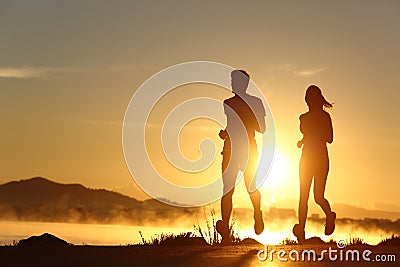 Silhouette of a couple running at sunset Stock Photo