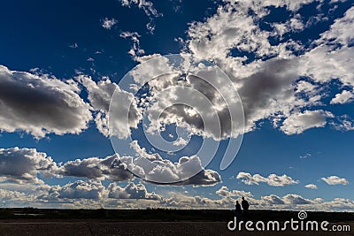 Silhouette of a couple taking a walk along the Kent coastline against a dramatic evening sky Stock Photo