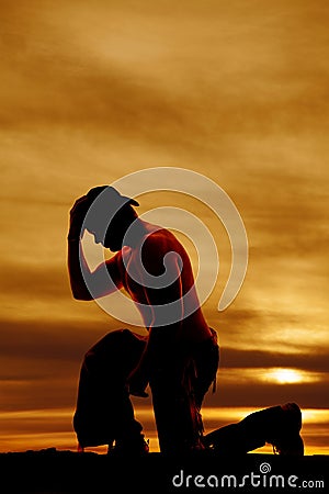 Silhouette cowboy no shirt kneel one knee hand on hat Stock Photo