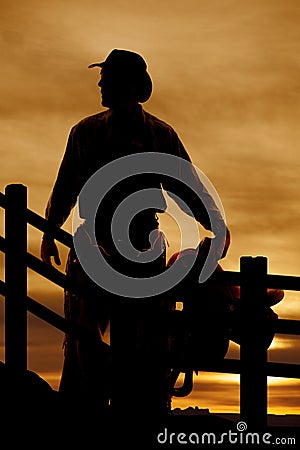 Silhouette cowboy saddle in front of fence Stock Photo