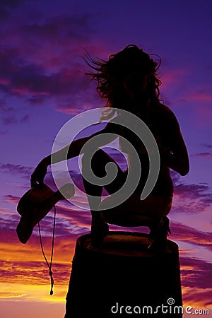 Silhouette cowgirl on barrel hold hat hair blow Stock Photo