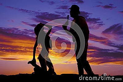 Silhouette cowgirl kneel on saddle look up at cowboy Stock Photo