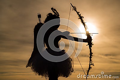 Silhouette of a cupid. Side view of teen girl archer against sunset. Cupid in valentine day - Valentine concept. Stock Photo