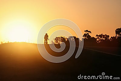 Silhouette of cyclist with an orange and yellow sky Stock Photo