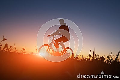 Silhouette of the cyclist riding a road bike at sunset Stock Photo