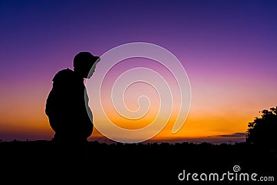 Silhouette dark young man wearing a hat standing emotions with evening Twilight sky with cloud in the winter season at sunset Stock Photo