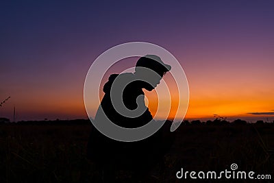 Silhouette dark young man wearing a hat standing emotions with evening Twilight sky with cloud in the winter season at sunset Stock Photo