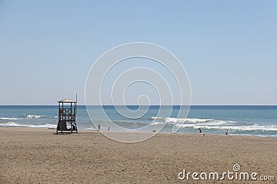 Silhouette of a distant anonymous tourist on the background of the sea on the sandy coast near the wavy sea during the Stock Photo