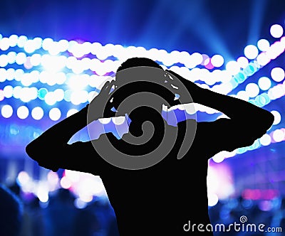 Silhouette of DJ wearing headphones and performing at a night club Stock Photo