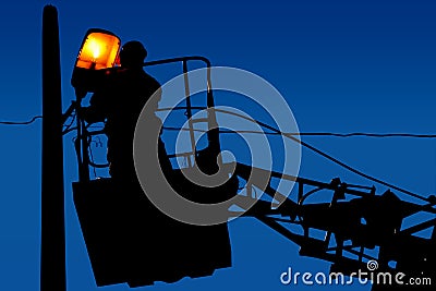 Silhouette electrician repairs on a light pole on the blue sky background Stock Photo