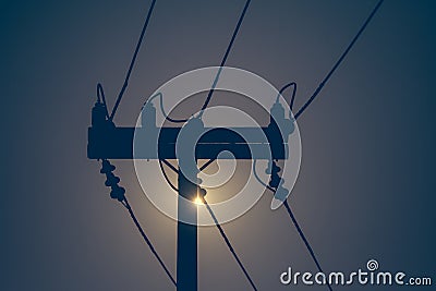 Silhouette of electricity pole and high voltage power line with sunset in the background. Stock Photo