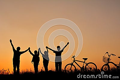 Silhouette of family with bicycle on grass field Stock Photo