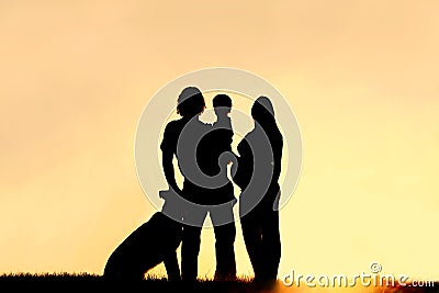 Silhouette of Family with Dog and Pregnant Mother at Sunset Stock Photo