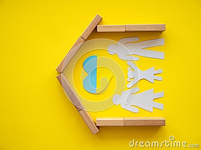 Silhouette of a family inside a wooden constructor house, a little girl pulls her hands up to a heart in the colors of the Stock Photo