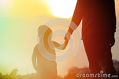 Silhouette of father and daughter holding hands at sunset Stock Photo