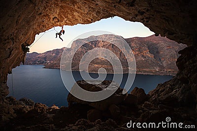 Silhouette of female rock climber on cliff in cave Stock Photo