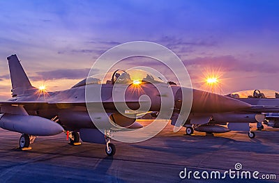 Silhouette fighter jet military aircrafts parked on runway in twilight sunset time with light airport Stock Photo