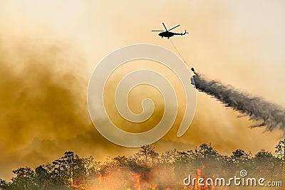 Silhouette firefithing helicopter dumps water on forest fire Stock Photo