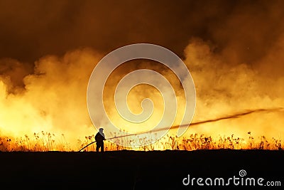 Silhouette of fireman fighting bushfire at night, man against the fire. Stock Photo
