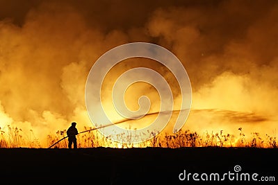 Silhouette of fireman fighting bushfire at night, man against the fire. Stock Photo