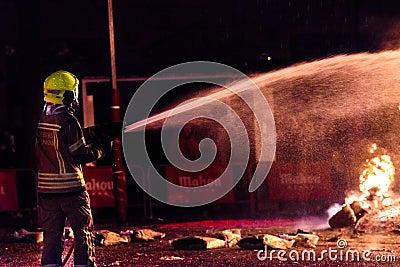 Silhouette of fireman trying to control a fire in a street during a night Stock Photo