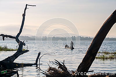 Silhouette fisherman on boat over bang phra reservoir near dead tree Editorial Stock Photo
