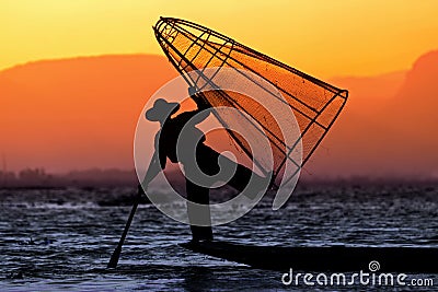 Silhouette of a fisherman in a boat with traditional Intha conical net in Myanmar Stock Photo