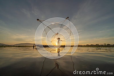 Silhouette Fisherman casting or throwing a net for catching freshwater fish in nature lake or river with reflection in morning Editorial Stock Photo