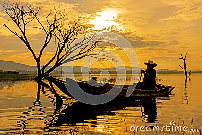 Silhouette fisherman on the fish boat on lake in the sunshine morning Stock Photo