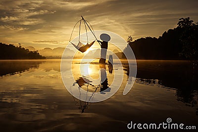 Silhouette of fisherman is fishing in the Lake during sunrise at Baan Nong Thale in Krabi Stock Photo