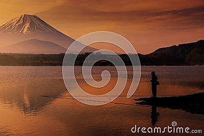 Silhouette fisherman fishing at Shoji lake with mount Fuji view reflection at dawn with twilight sky in Yamanashi Stock Photo