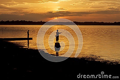 Silhouette fisherman of Lake in action when fishing. Stock Photo